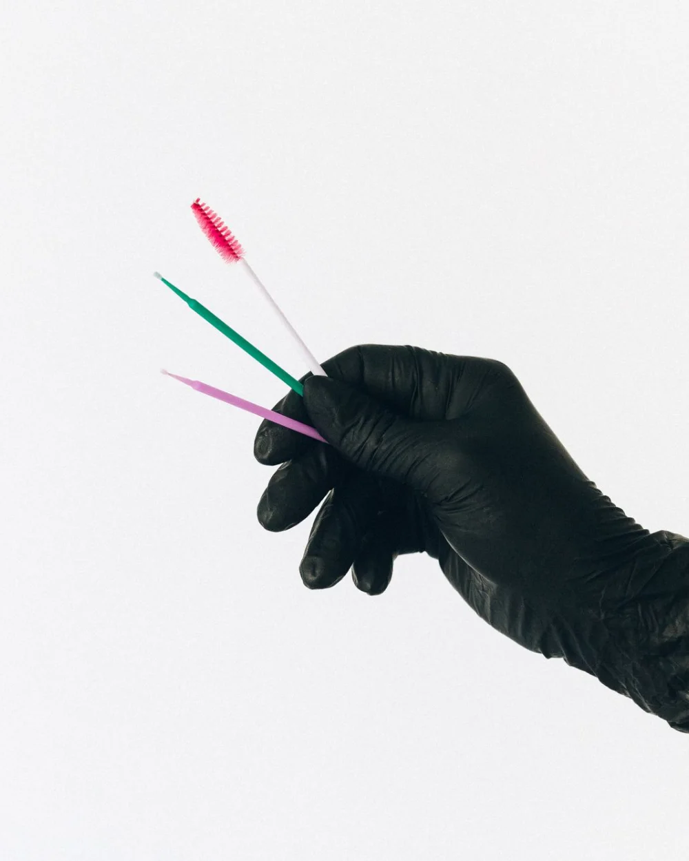 Mano con guante sujetando microcepillos de colores