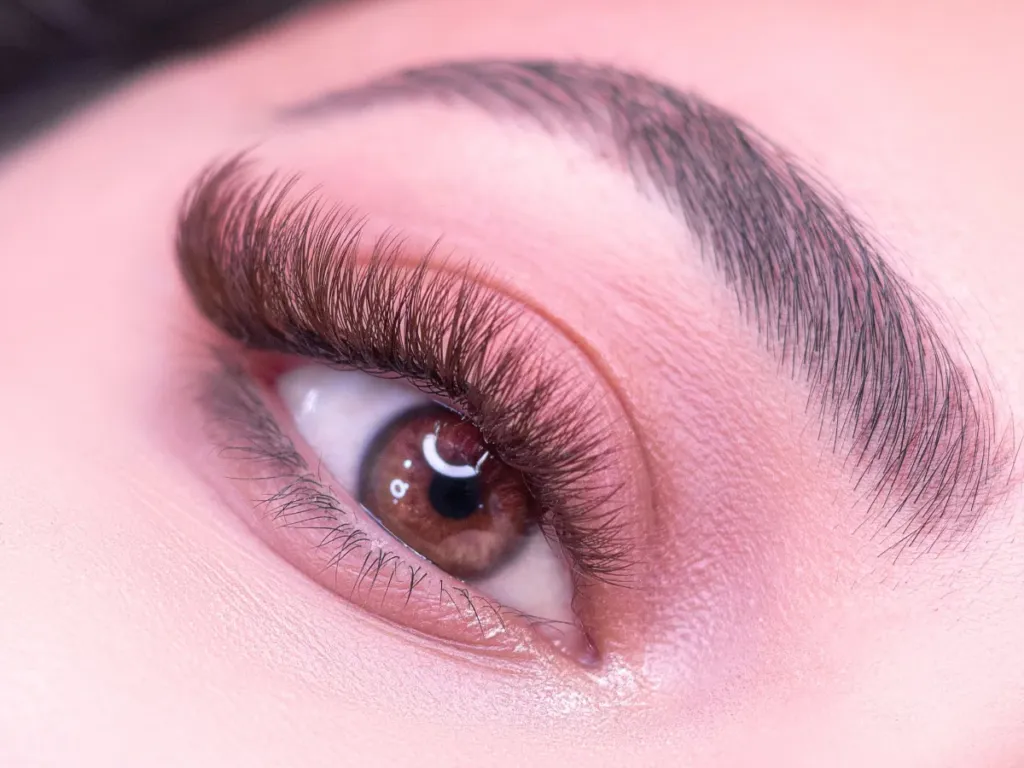 Ojo con extensiones de mega volumen y maquillaje rosa